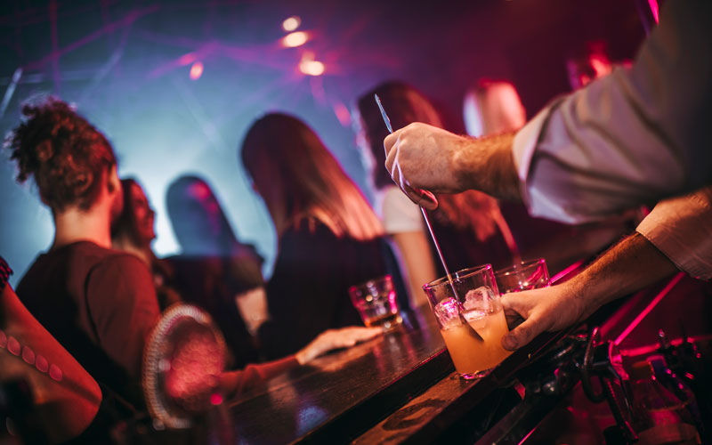 bartender mixing cocktail behind bar at nightclub