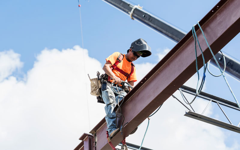 man climbing on high rise steel beam