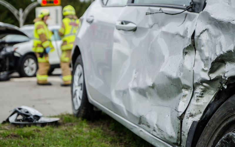 closeup of car accident where one car is severely damaged on one side