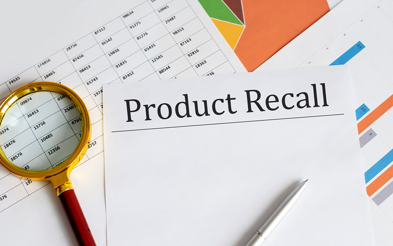 product recall graphic with magnifying glass, paper work, and a pen